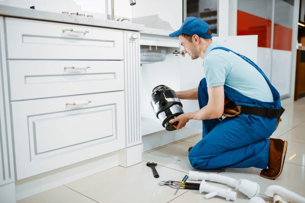 Male plumber in uniform installing disposer