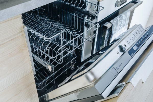 Open empty dishwasher machine close-up in modern kitchen.